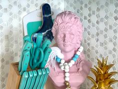 there is a pink statue next to some pineapples and other kitchen utensils