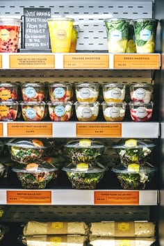 a display case filled with lots of different types of salads and fruit in plastic containers