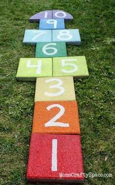 a number line made out of blocks in the grass with numbers painted on it, and two