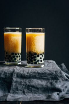 two glasses filled with liquid sitting on top of a table next to a black cloth