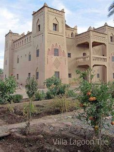 an old building with many windows and balconies on the outside, surrounded by fruit trees