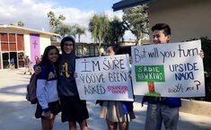 three people holding signs in front of a building with palm trees and buildings behind them