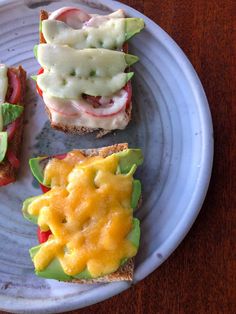 three sandwiches with cheese, tomato and avocado on them sitting on a plate