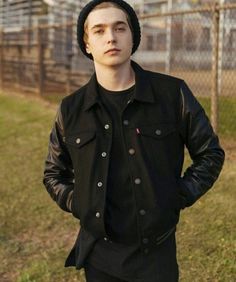 a young man wearing a black jacket and hat