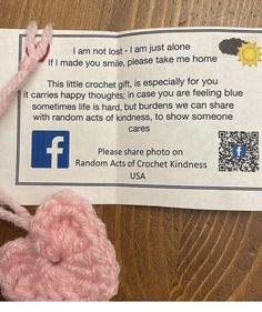 a pink crochet heart on top of a piece of paper next to a qr code