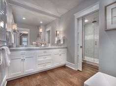 a large bathroom with white cabinets and wood floors