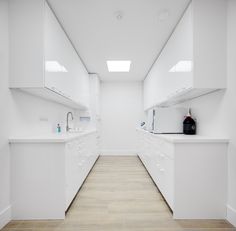 an empty kitchen with white cabinets and counter tops on the walls, along with wood flooring