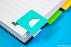 an open notebook with the letter d cut out and colored sticky notes attached to it