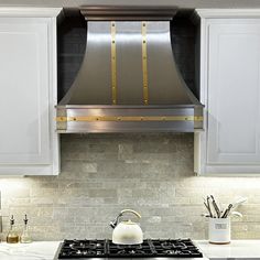 a stove top oven sitting inside of a kitchen next to white cabinets and counter tops