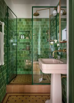 a green tiled bathroom with a sink and shower