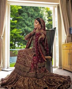 a woman in a red and gold wedding dress sitting on a chair