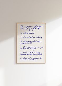 a white wall with blue writing on it and a wooden frame hanging from the wall