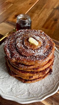 a stack of pancakes sitting on top of a white plate covered in powdered sugar