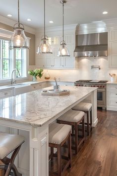 a large kitchen with white cabinets and marble counter tops, an island in the middle