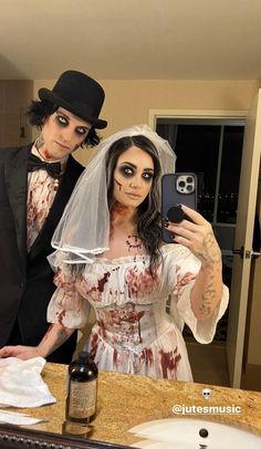 a man and woman dressed up as zombies taking a selfie in a bathroom mirror