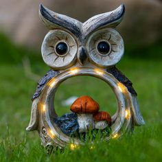 an owl figurine sitting in the grass with its eyes open and lights on