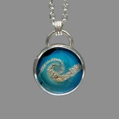 a necklace with an image of a wave in the ocean on it's side