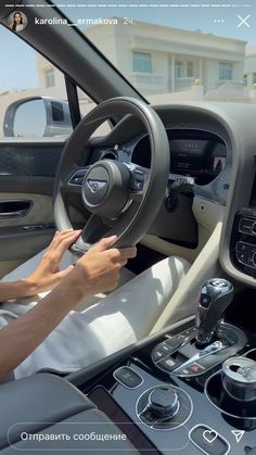 the interior of a car with steering wheel and dashboard controls in front of a white building