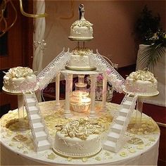 an elaborately decorated wedding cake sits on top of a table with white flowers and ribbons