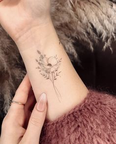 a woman's wrist with a flower tattoo on her left arm and the other hand