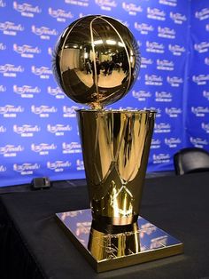 a golden trophy sitting on top of a table next to a blue wall in front of a sign