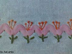 some pink flowers and green leaves on a white cloth with red thread in the middle