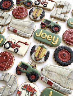 decorated cookies with tractors and farm vehicles are displayed on a white tablecloth covered surface