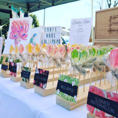 there are many lollipops on display at the market table with price signs