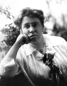 an old black and white photo of a woman holding her hand to her face with flowers in the background