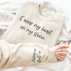 I wear my heart on my sleeve mom sweatshirt All sweatshirts are made with Gildan unisex style tops.  They are cozy and fleece lined.  They run true to size but if you prefer a fitted look size down, and if you prefer an oversized look size up one.  Treat yourself to this custom sweatshirt, or give it as a thoughtful gift to a mother or grandmother. SHIPPING: All orders will be shipped using USPS ground shipping (2-5 business days) unless you have upgraded. I always aim to get your items out as quickly as possible but if you need something to arrive by a certain time please message me and I'll do my best. SOCIAL MEDIA:   Follow me on Instagram to be the among the first to see new items and snag discounts @thechelleshoppe.  I absolutely love seeing how you style your shirts so please feel fr Mom Sweaters Vinyl, Heart On My Sleeve Sweatshirt, Wear My Heart On My Sleeve Shirt, Personalized Mother Gift, I Wear My Heart On My Sleeve Svg, I Wear My Heart On My Sleeve, Personalized Long Sleeve Cotton Sweatshirt, Mother's Day Sweatshirt With Custom Text, I Wear My Heart On My Sleeve Sweater