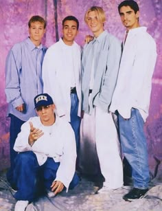 a group of young men standing next to each other in front of a purple background