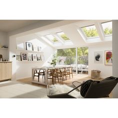 an open living room and dining area with skylights on the roof, white walls