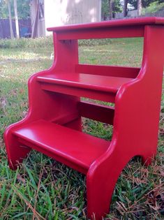 a red plastic step stool sitting in the grass