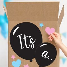 a person holding up a box with balloons on it that says it's a boy