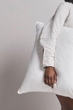 a woman holding a pillow in her right hand