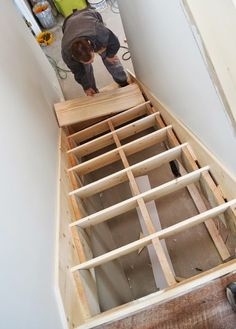 a man standing on top of a wooden floor next to a ladder in a room