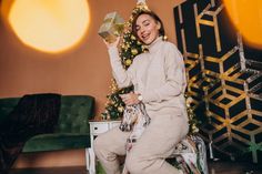 a woman sitting on top of a wooden floor next to a christmas tree