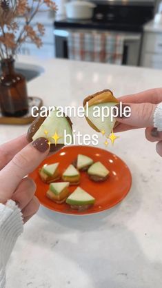 someone is holding an apple slice on a plate with other food items in the background