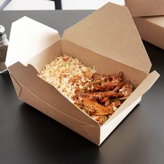 an open take out box filled with rice and meat next to a salt shaker