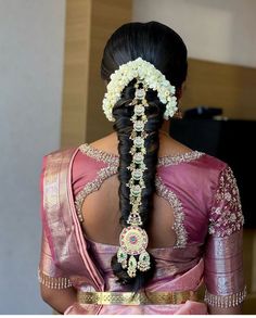 the back of a woman's head with braids and flowers in her hair