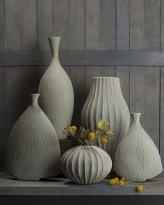 four white vases sitting on top of a table next to each other with yellow flowers in them