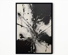 a black and white painting hanging on the wall with paint splatters all over it