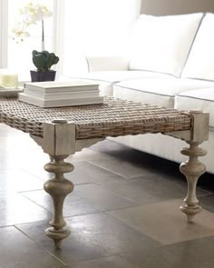 a white couch sitting next to a table on top of a tiled floor in front of a window