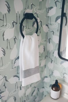 a white towel hanging on the wall next to a bathroom sink with a mirror and soap dispenser