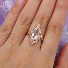 a woman's hand wearing a ring with an oval shaped pink stone in the center