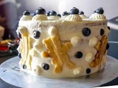 a cake with blueberries and bananas on it sitting on top of a metal platter