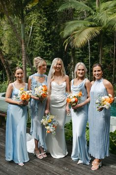 a group of women standing next to each other on a wooden platform in front of trees