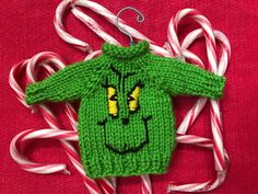 a green knitted sweater hanging from a christmas ornament with candy canes