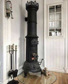 an old fashioned stove in a room with wood flooring and white paint on the walls