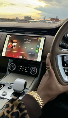 a woman driving a car with her hands on the steering wheel and an electronic screen